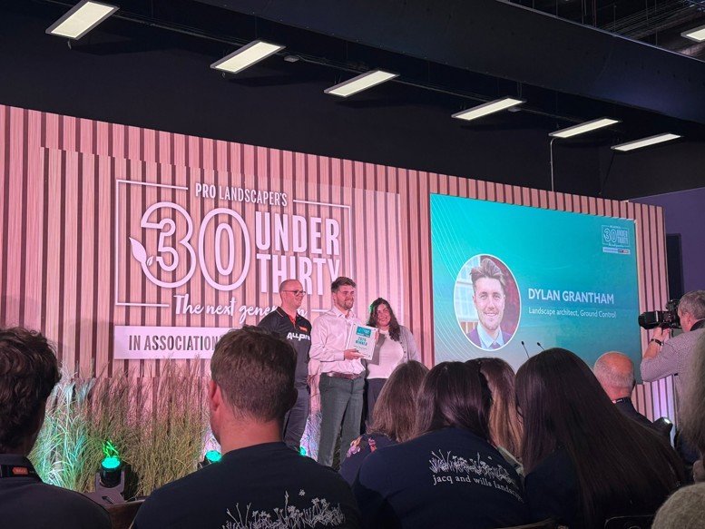 Three people on stage at the Pro Landscaper 30 Under Thirty awards ceremony, with an award recipient holding a certificate.