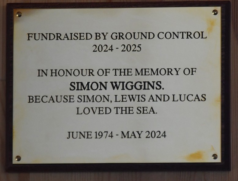Plaque reading "Fundraised by Ground Control 2024-2025. In honour of the memory of Simon Wiggins, becuse Simon, Lewis and Lucas loved the sea. June 1974-May-2924"
